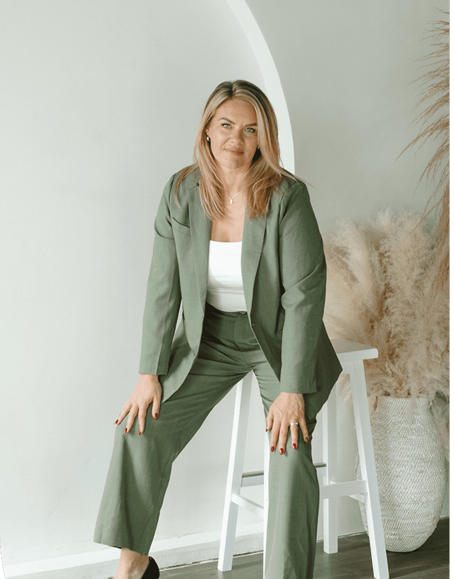 Woman in green suit sitting on a white stool.