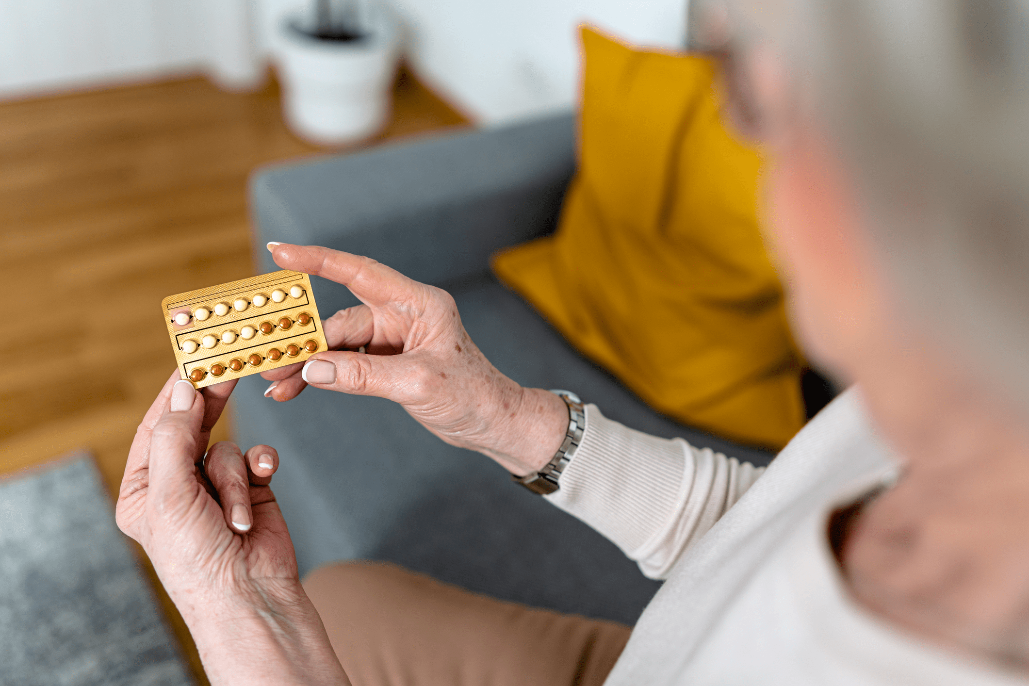 An elderly person holding a blister pack of medication.